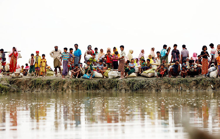 Rohingya refugees are seen waiting for a boat to cross the border through the Naf river in Maungdaw, Myanmar